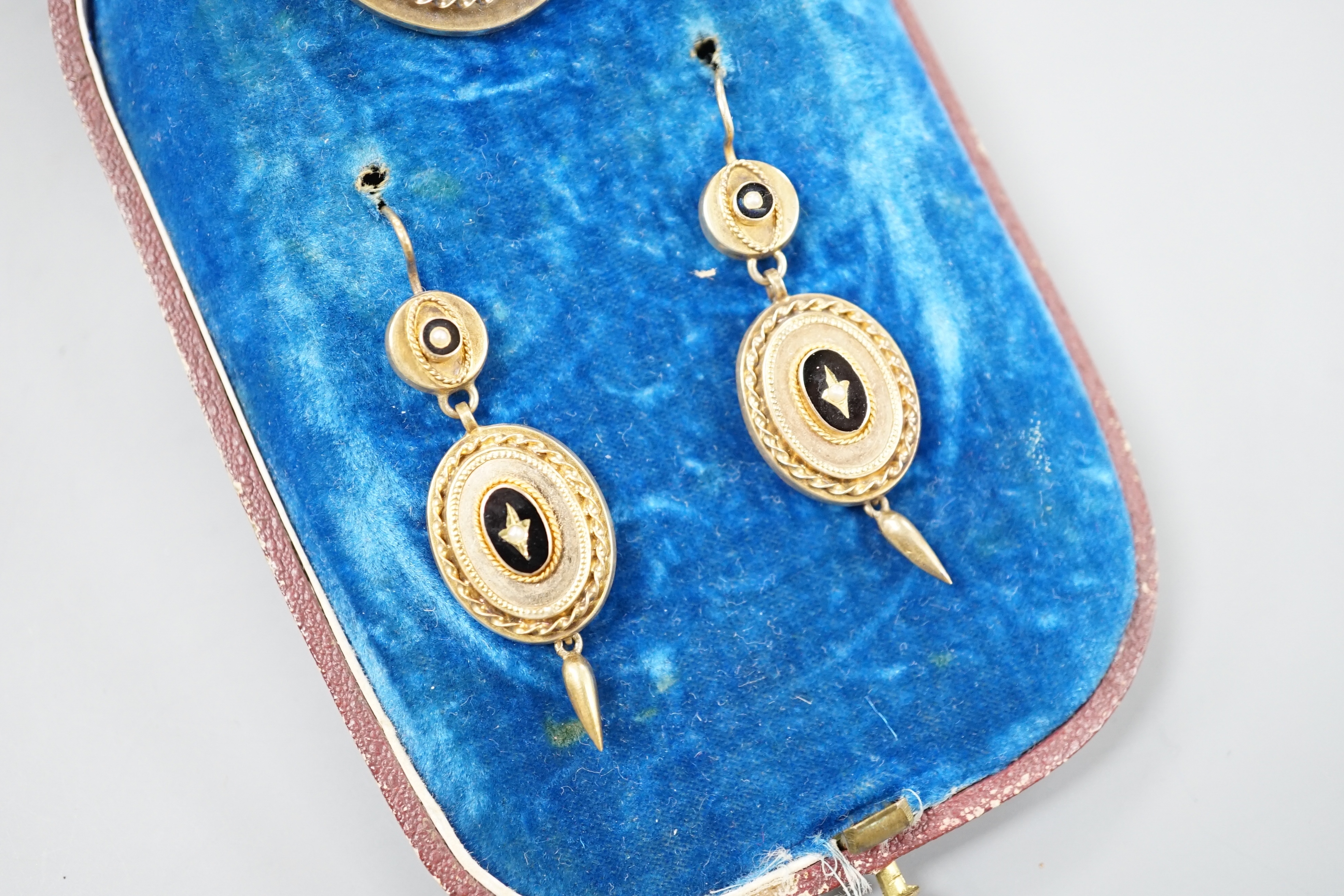 A cased Victorian yellow metal, black enamel and seed pearl set brooch, 35mm and matching pair of drop earrings, gross 13.6 grams.